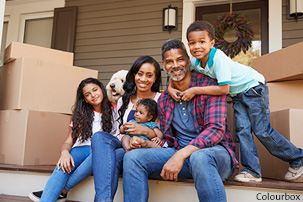 Family sitting outside their house surrounded by boxes