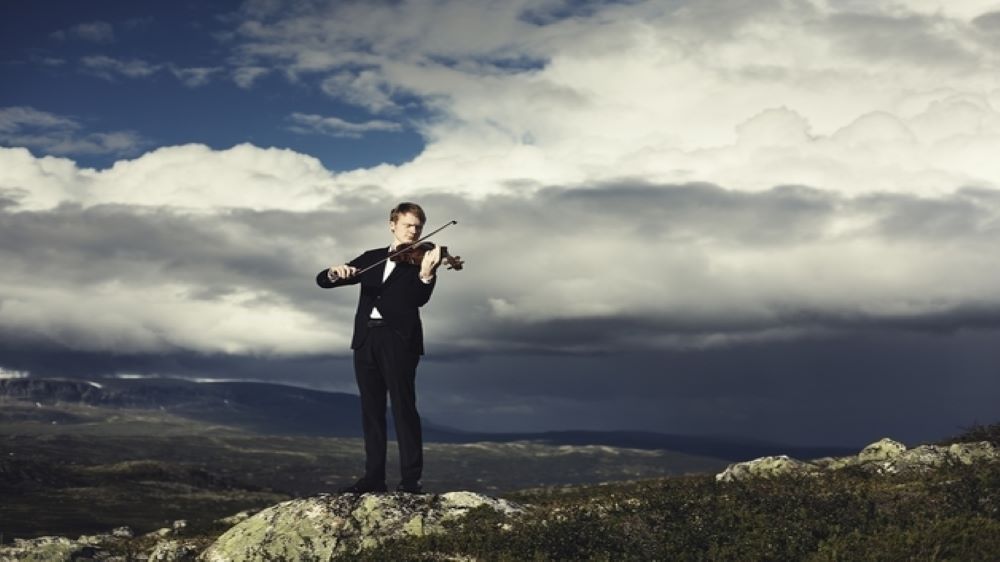 Man on top of mountain playing violin
