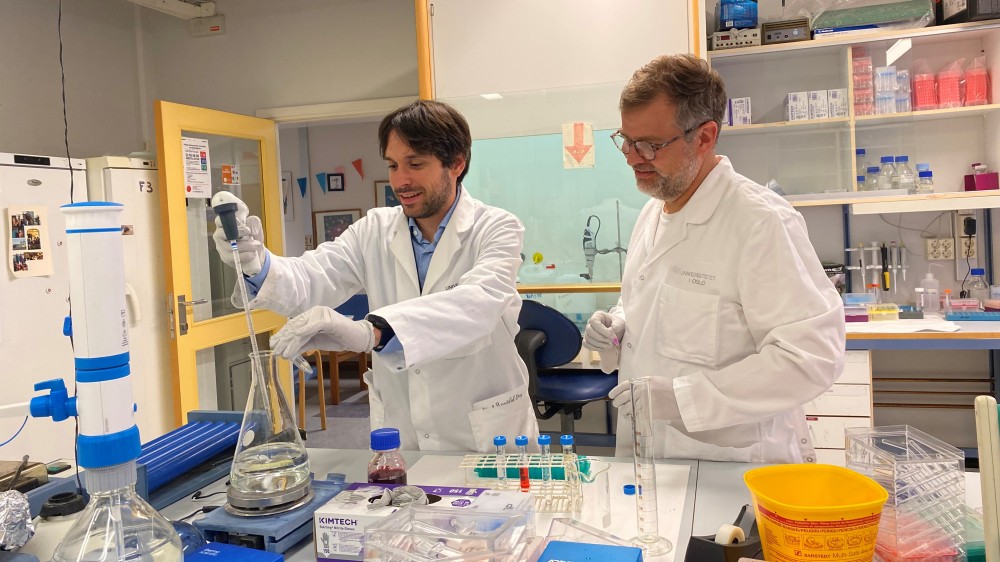 Image shows two researchers in a lab working with a bulb pipette