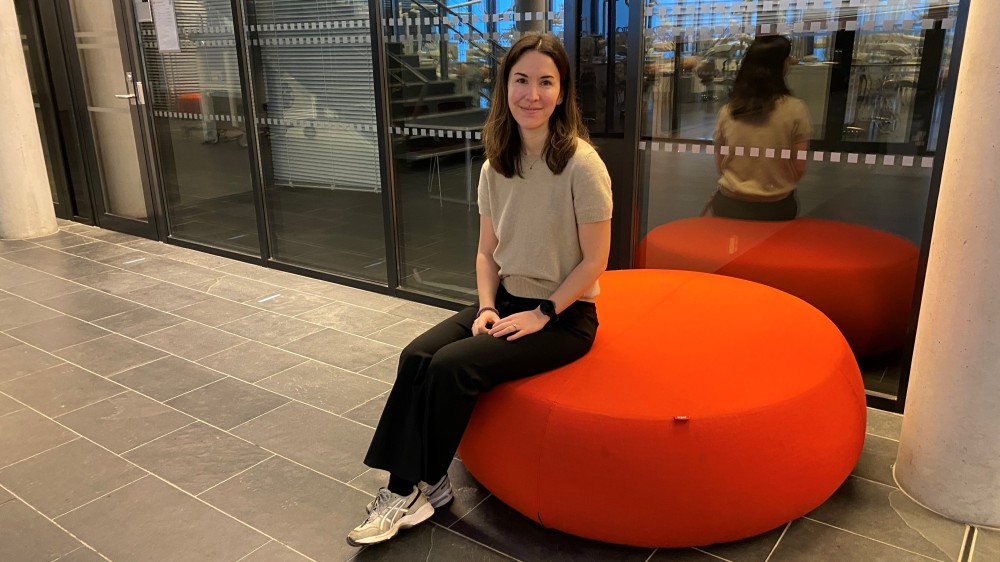 Image shows a woman with dark hair sitting on an orange coloured chair