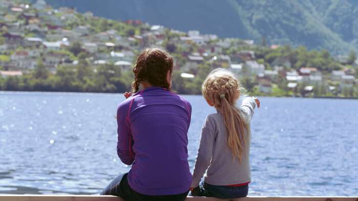 Image of two girls sitting by a Norwegian fiord 
