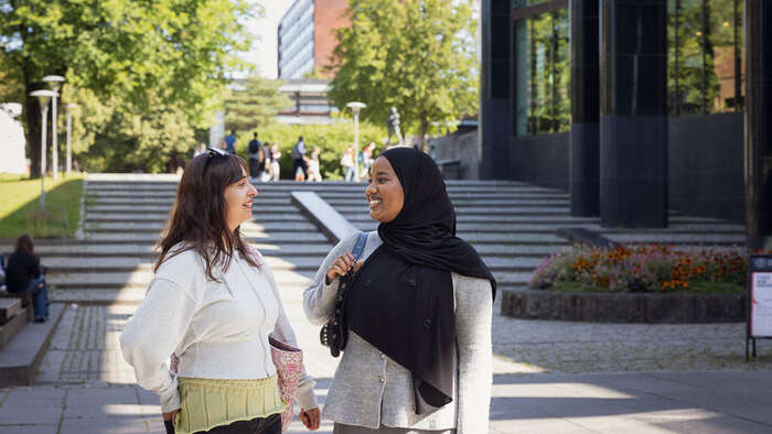 Two students in conversation outside the University Library