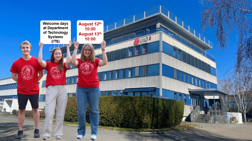 Three students in red university t-shirts holding up welcome signs