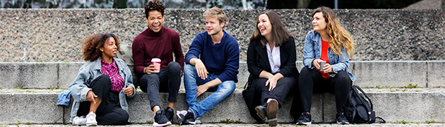 Group of students sitting together on stairs made of stone.