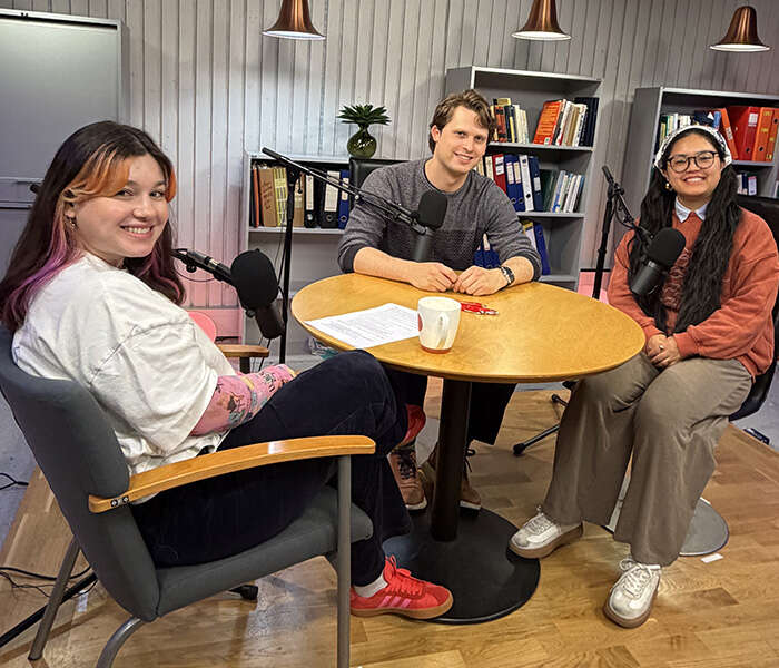 Three people sitting around a table, smiling at the camera