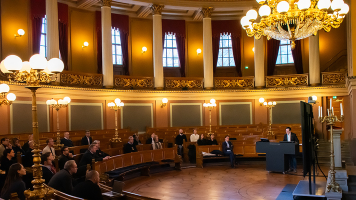 Mann holder foredrag i gammel festsal på universitetet.