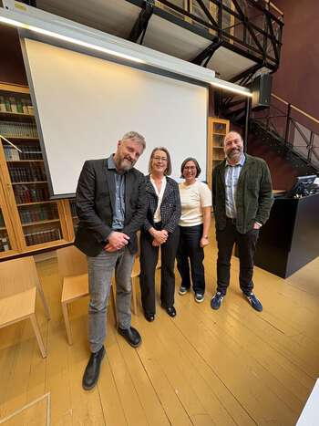 Gruppebilde av to menn og to kvinner i auditorium.