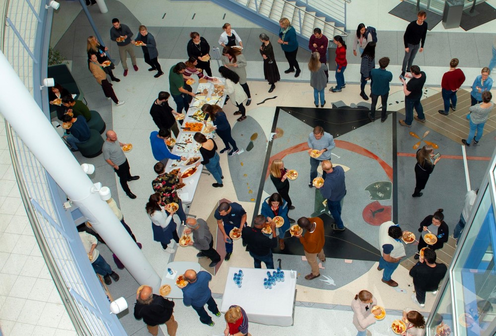 Bildet viser mennesker som står rundt bord med mat og snakker