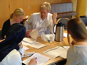 Fire personer i diskusjon rundt et bord med papirer
