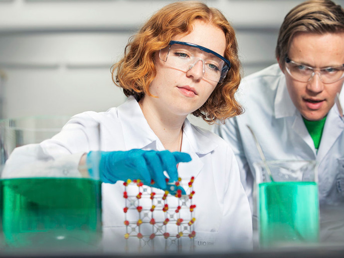 To forskere ser på en molekylmodell og glass med grønn væske