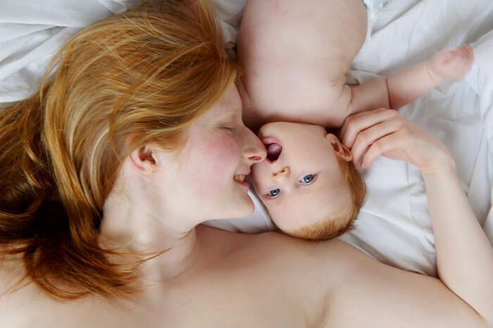 Kvinne som ligger i en seng sammen med en baby