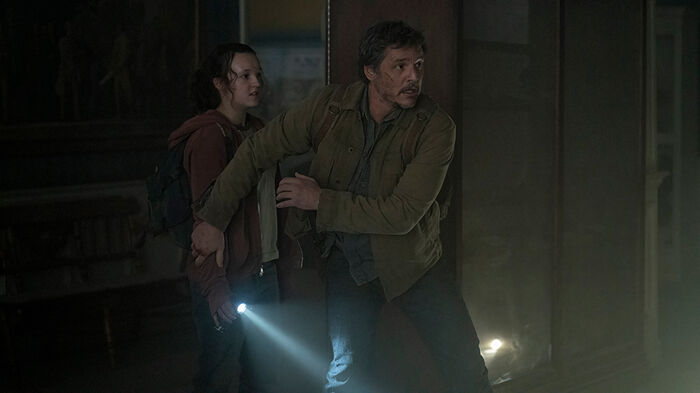 En ung kvinne og en mann med lommelykt. Scene fra TV-serien "The last of us". Foto.