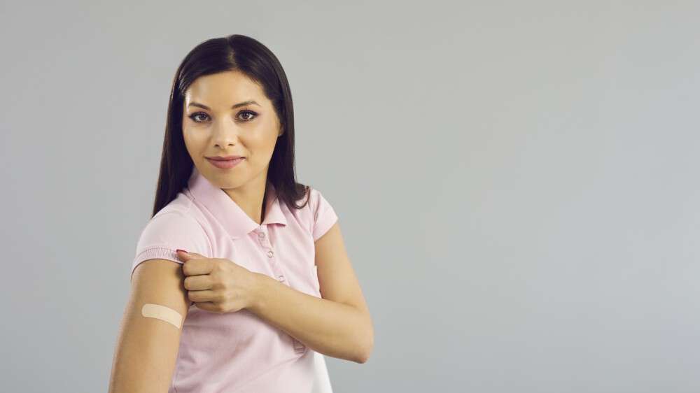 Bildet viser en kvinne som viser fram en bar arm med et plaster på
