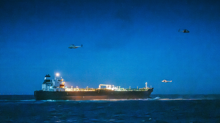 Bilde av en gammel oljetanker og helikoptere rundt skipet