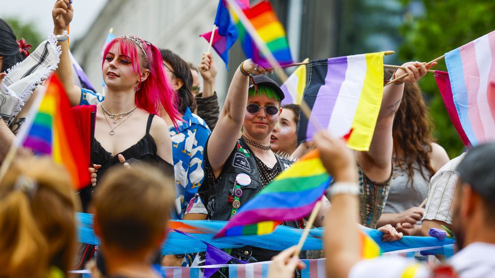 Fra pride-paradden i Oslo - to personer omgitt av Pride-flagg 