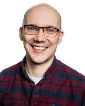 Ung smilende mann med rødrutetet skjorte og briller