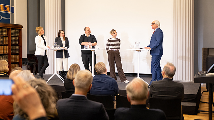 Panelsamtale på scenen. Tre kvinner og to menn snakker sammen.