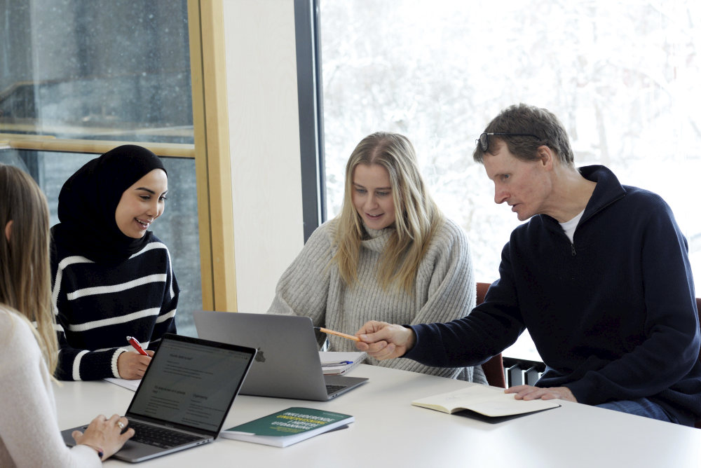 Bilde av en gruppe mennesker som diskuterer det de ser på en pc-skjerm