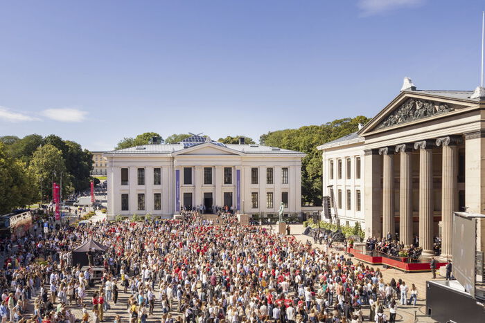 Universitetsplassen under velkomstseremonien for nye studenter. Det er blå himmel og plassen er full av studenter og faddere i røde t-skjorter.
