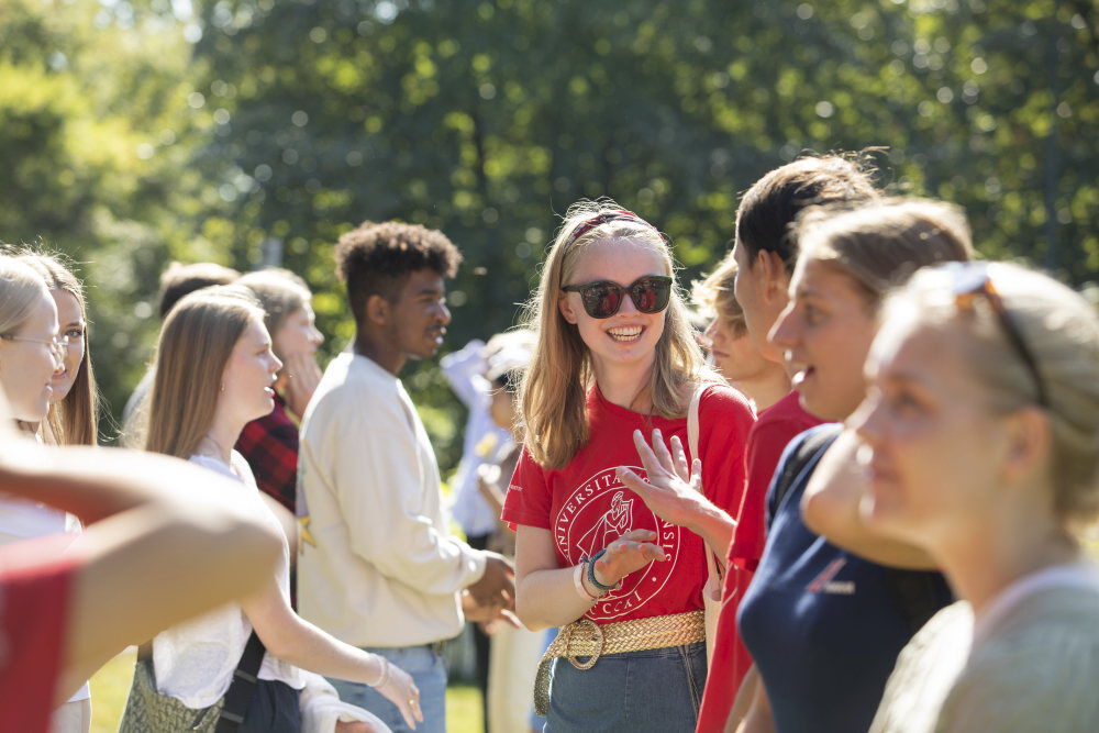 Unge studenter samlet i grømme omgivelser på campus. 