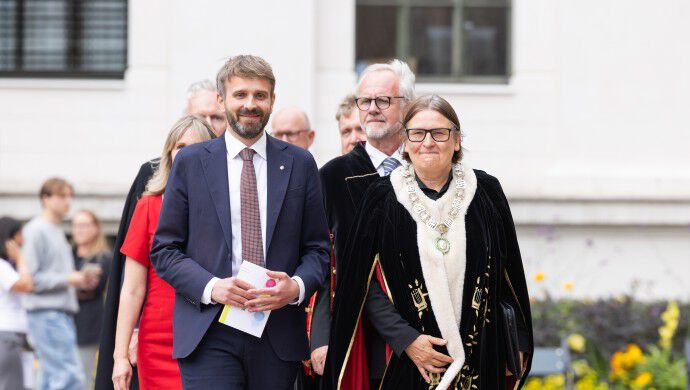 Helse- og omsorgeminister Jan Christian Vestre og rektor Ragnhild Hennum kommer gående mot kamera ute på Universitetsplassen.