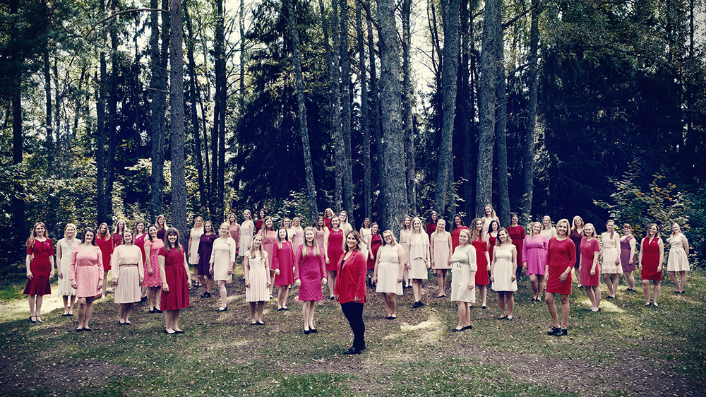 Bilde av alle kormedlemer i Kvindelige Studenters Sangforening med trær i bakgrunnen