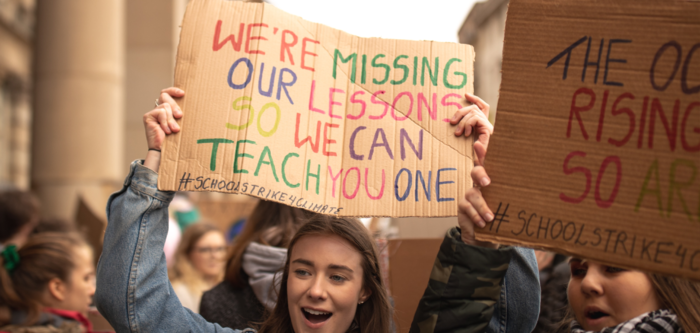 Skoleelev holder plakat der det står we`re missing our lessons so we can teach you one. Illustrasjonsfoto.