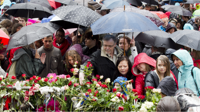Bilde fra rosetog etter 22. juli for ti år siden. Paraplyer, regn, folk, roser.