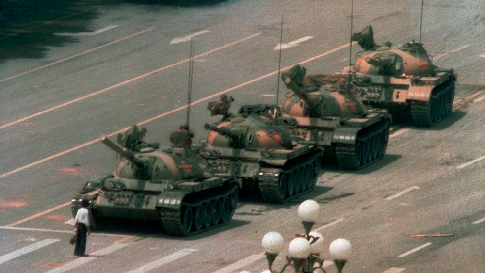 En mann står foran fire tanks.