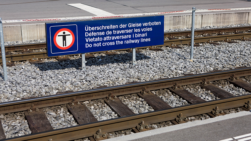 Togspor og et skilt med beskjed på flere språk.
