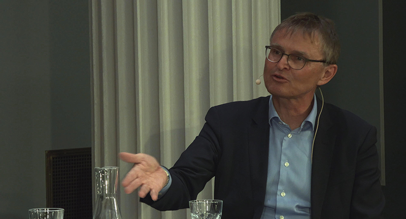 Egil Tjåland snakker på scenen i Domus Bibliotheca