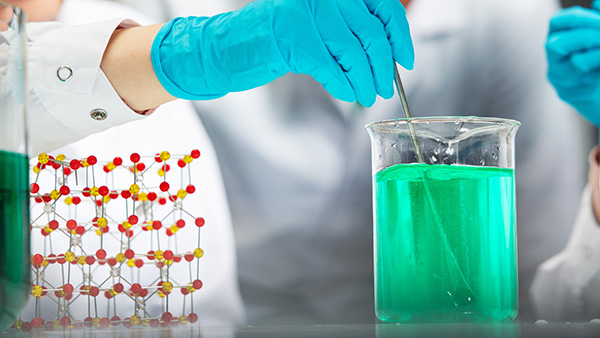 Hånd med gummihanske som rører i grønn veske ved siden av en molekylmodell