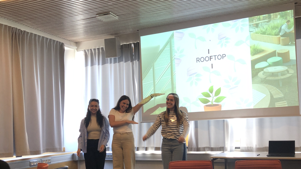 Tre studenter foran en presentasjon av IFIs takterasse.