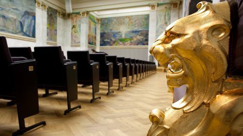 Image of the University aula with a gilded lion's head in front