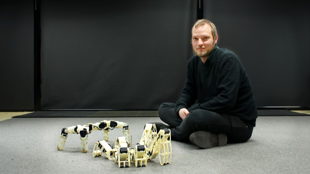 Mann sitter på gulvet med roboter.