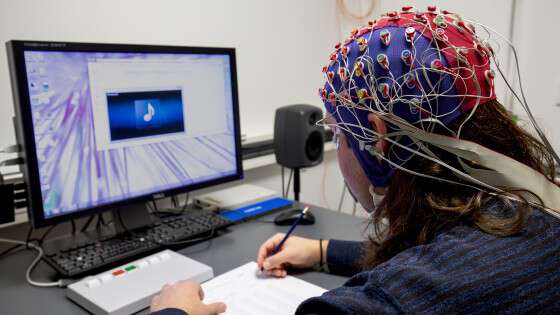 Man in EEG cap in front of a computer screen.