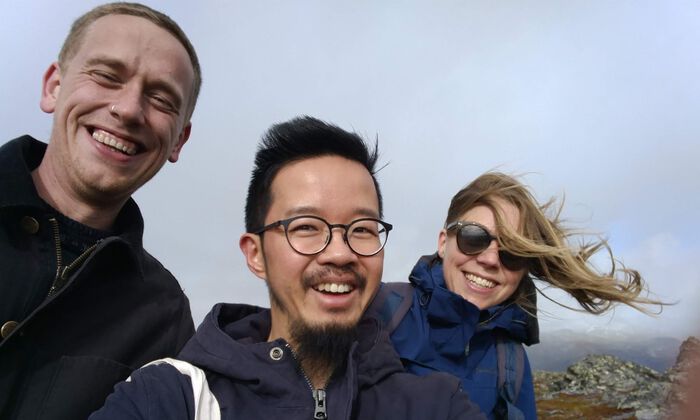 Three people smiling on a mountain 