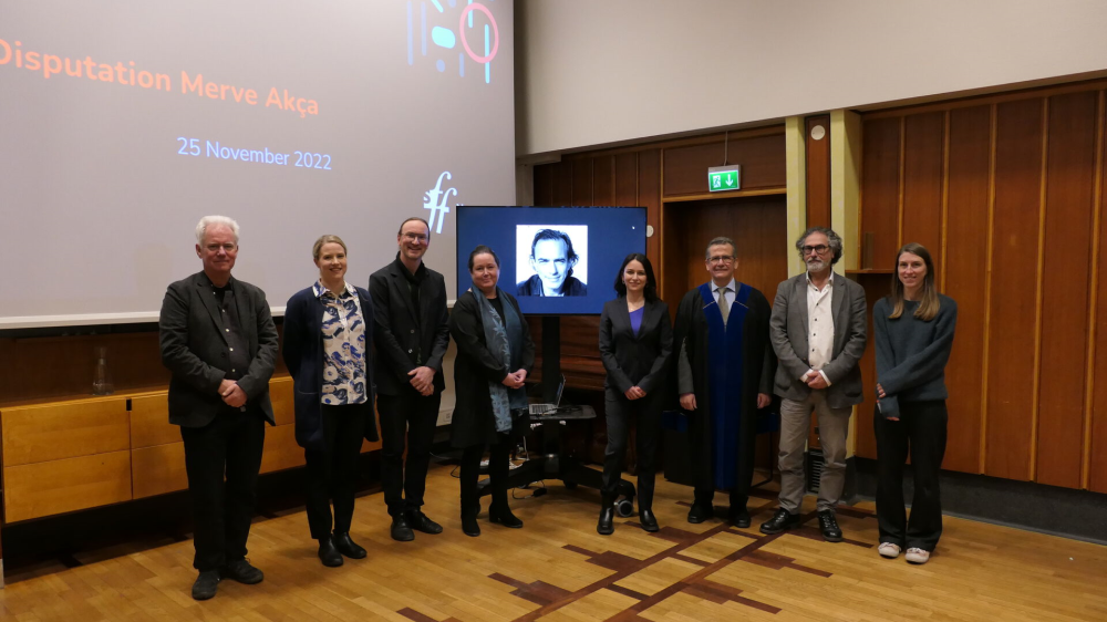 Merve with supervisors, opponents, and disputation leader. One opponent is on a TV screen with a picture