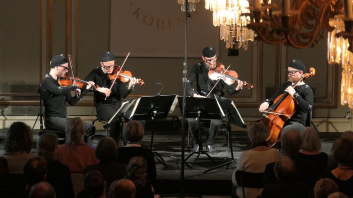 The Danish String Quartet seated on a small stage playing music.