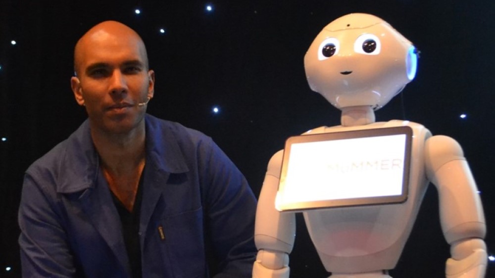 Man on the left of a white robot with a screen on its chest