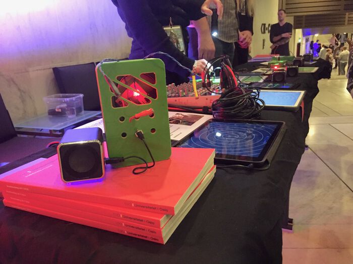 A stack of books with a technical construction connected to a speaker on top. Photo.