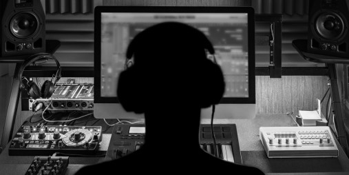 Bakhodet på en person med headset og som ser på en PC. Foto.