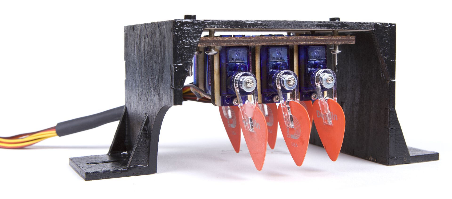 A boring and not at all kinetic plucking mechanism mostly enclosed inside a black plywood housing.
