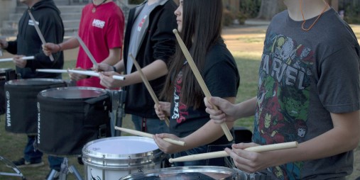 Drums, and the hands of a drummer holding drumsticks.