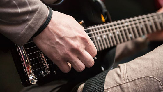 Utsnitt av bilde av mann som spiller gitar - hånd og gitar