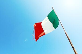 Bildet viser det italienske flagget vaiende i vinden, mot en blå himmel