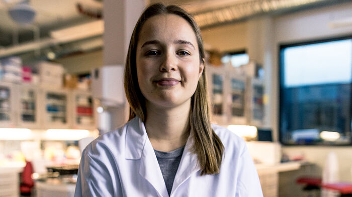 En student med labfrakk inne på laboratoriet. 