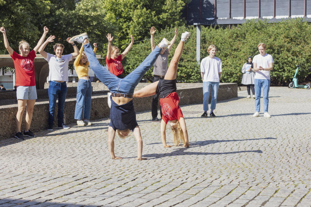 Fire studenter som smiler og holder rundt hverandre. 