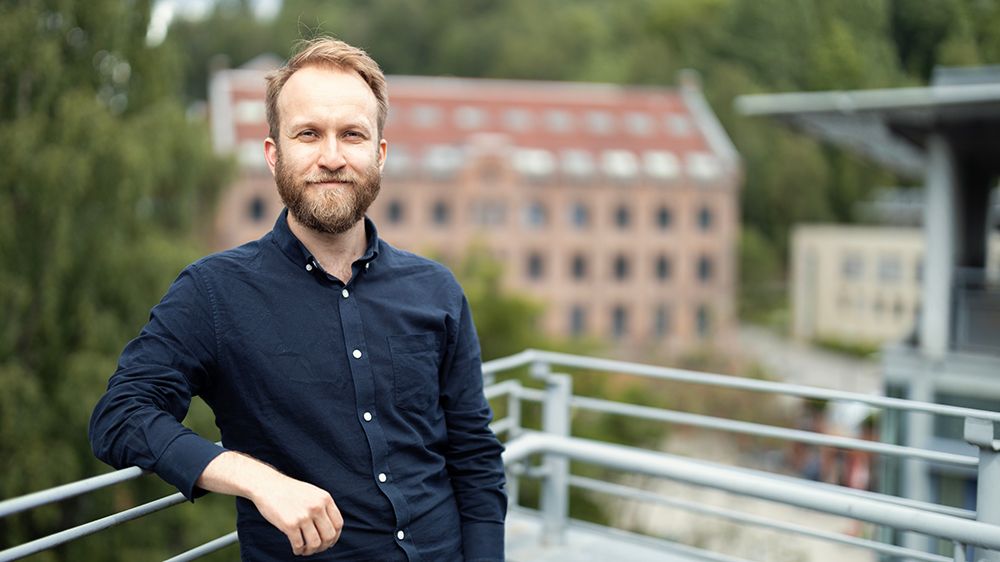 Ung mann som lener seg mot rekkverket på en veranda.