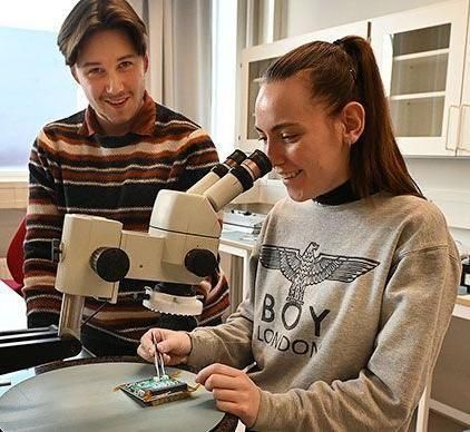 To studenter i undervisningsrommet. En som ser på chip i teleskop.
